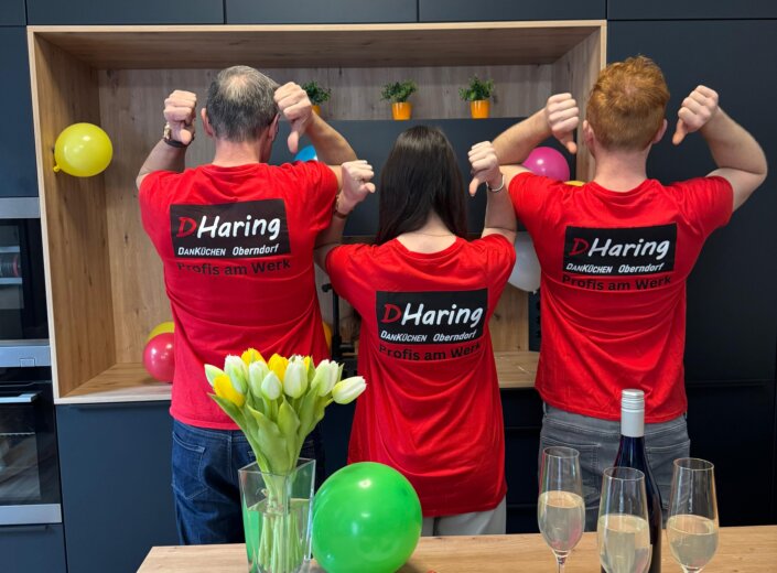 Teamfoto auf der Hausmesse von hinten, auf den T-Shirts steht ein Text mit "Profis am Werk".