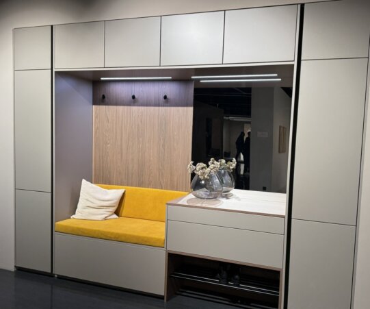 Helle Garderobe mit deckenhohen Schränken, integrierter Sitzbank, viel Stauraum und einem Spiegel.